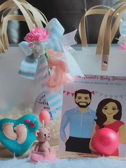 A close-up of the baby shower hamper contents, including a teddy candle and a baby-feet soap.