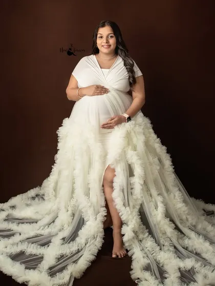 A solo portrait is a powerful way to document your journey. This mother-to-be looks absolutely radiant in a classic white ruffled gown against a simple studio backdrop, highlighting her beautiful pregnancy glow.
