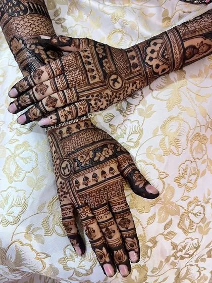 A closer look at the personalized initials 'M' and 'K' on the back of the hands. The letters are framed beautifully within the intricate bands of the bridal design.