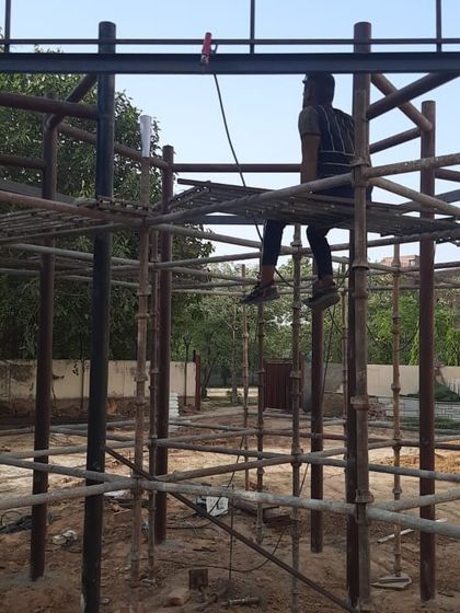A worker on the scaffolding of a play structure, showing the complexity of the fabrication process.