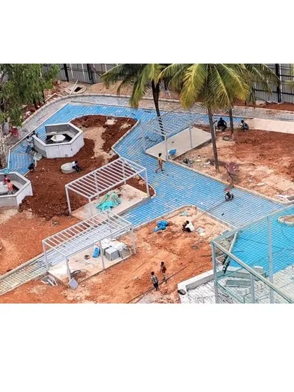 An aerial view of workers laying pavers for the pathways at Vaishnavi Tech Square. The distinct blue color and geometric pattern are key features of the design.