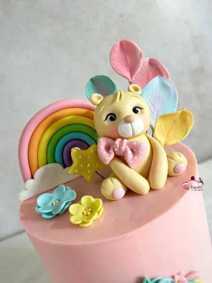 A close-up of the sweet teddy bear topper with his pastel rainbow and balloon-like petals.