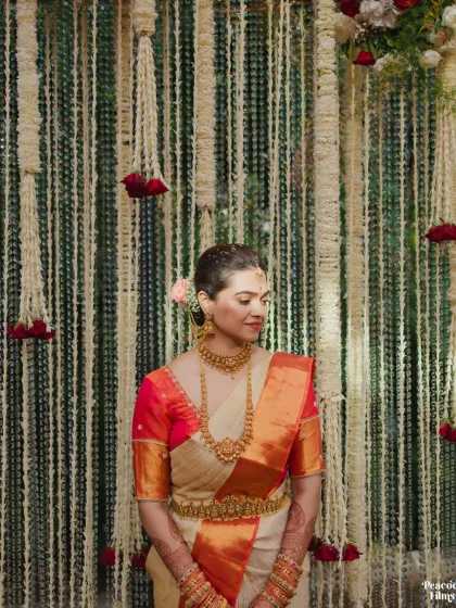 A quiet moment for the bride against a backdrop of hanging flowers. Her traditional gold jewelry and silk saree are the epitome of South Indian grace.