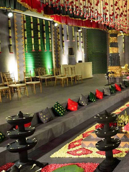 A view of the guest seating along the tiered platforms of the temple setup. The space is decorated with traditional stone lamps (deepams), colorful cushions, and floral runners, ensuring every detail contributes to the authentic temple atmosphere.