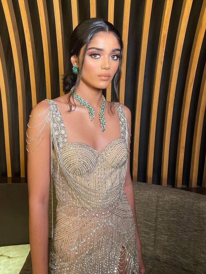 A close-up of a modern, glamorous look with a beaded gown. The makeup is soft and romantic, with a focus on a peachy glow.