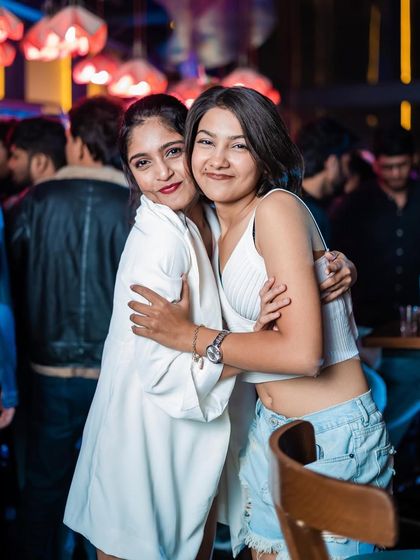 Two friends sharing a hug and a smile at The Fixx Bar.