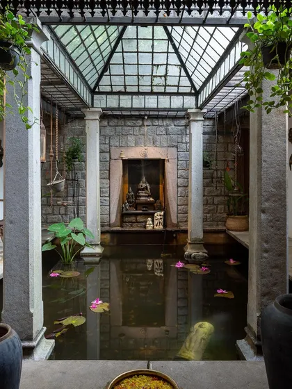 The stunning indoor pond in our Heritage Villa, with a glass ceiling, stone pillars, and a serene Buddha statue, creating a tranquil oasis.
