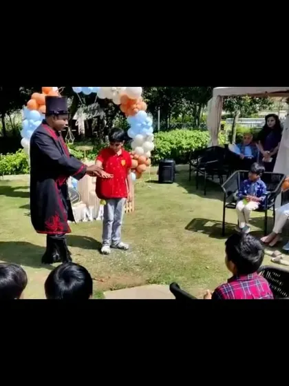 An interactive trick with a young volunteer during an outdoor garden party. The show works wonderfully in different environments, bringing magic wherever it's needed.