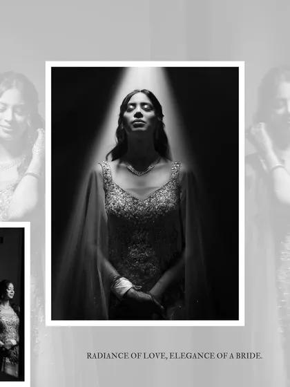 A dramatic black and white bridal portrait. The bride stands under a single spotlight, creating a powerful, artistic image that emphasizes her radiance.