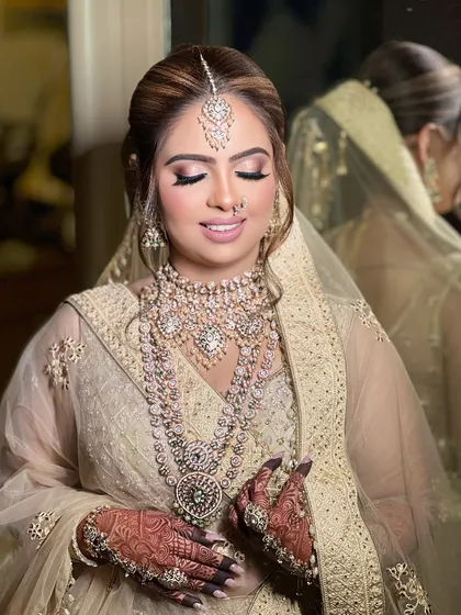 A portrait of the bride against a mirror, showing her reflection and the stunning details of her jewellery from another angle.