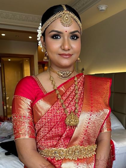 My beautiful South Indian bride, Deepika, looking absolutely radiant. Her look features a classic red Kanjeevaram saree, temple jewelry, and a neat bun adorned with fresh jasmine flowers (gajra).