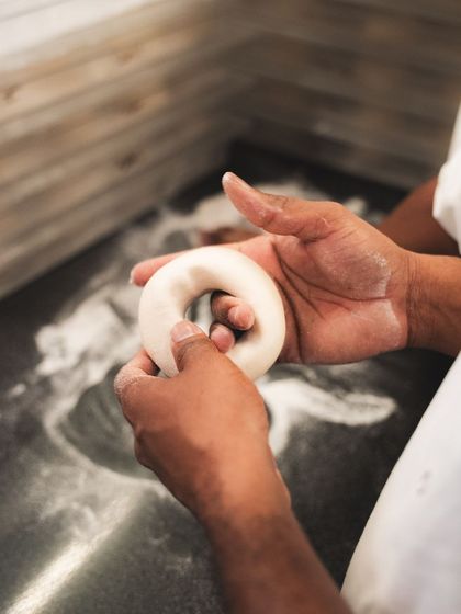 A baker's hands shaping a bagel from our signature dough.