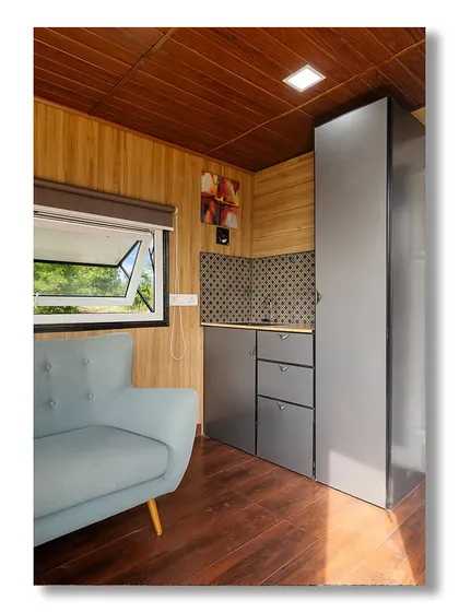 The interior of 'The Boulder Nest,' a container home designed for sustainable luxury. The compact kitchenette and cozy seating area show how every inch of space is used efficiently and stylishly.