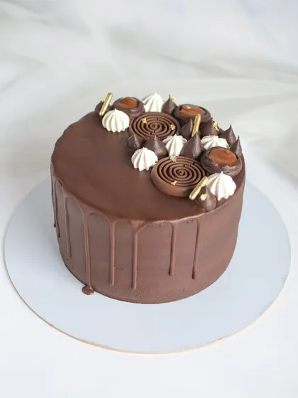 A delicious Chocolate Salted Caramel drip cake. This cake balances rich dark chocolate frosting with a sweet and savory salted caramel filling, decorated with chocolate spirals and meringue kisses.