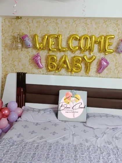 A 'Welcome Baby' girl bedroom setup with foil letters, 'BABY' blocks, and balloon pillars in pink and rose gold.