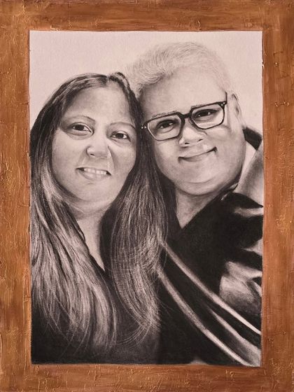 A custom portrait like this makes for a perfect and memorable gift. This charcoal drawing captures a warm moment between a couple, framed and ready to be cherished for years to come.