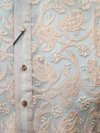 A close-up of the delicate threadwork on one of our kurtas. This peach-colored embroidery on a light base is a perfect example of our craftsmanship.