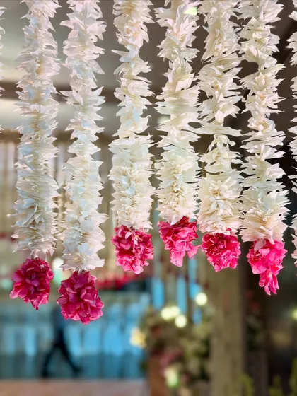 A detailed shot of the hanging white and pink floral strings, highlighting the craftsmanship and the delicate beauty of the individual elements.
