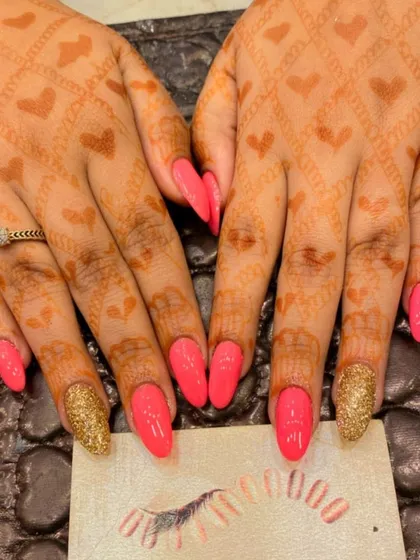 A bright and joyful bridal set. The coral pink nails and gold glitter accent nails are a perfect match for the heart-themed mehendi, creating a cohesive and celebratory look.