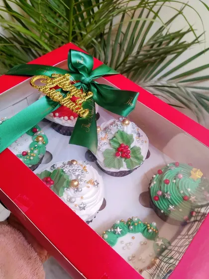 Getting into the festive spirit with my Christmas cupcakes. This box of six features detailed holiday designs like wreaths, holly, and a Santa hat, all packed in a beautiful red gift box tied with a green ribbon.