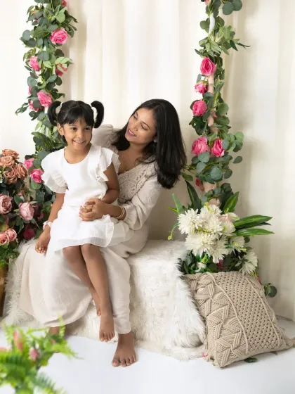 A mother sits with her daughter, sharing a quiet, loving moment together in our dreamy floral-themed studio.