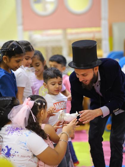 Children gather around the magician, fascinated by the appearance of a live dove. These interactive moments are always a crowd-pleaser.