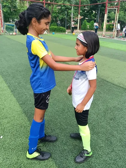 True strength lies in lifting others up. An older player congratulates a younger teammate, showcasing the spirit of our girls' program.