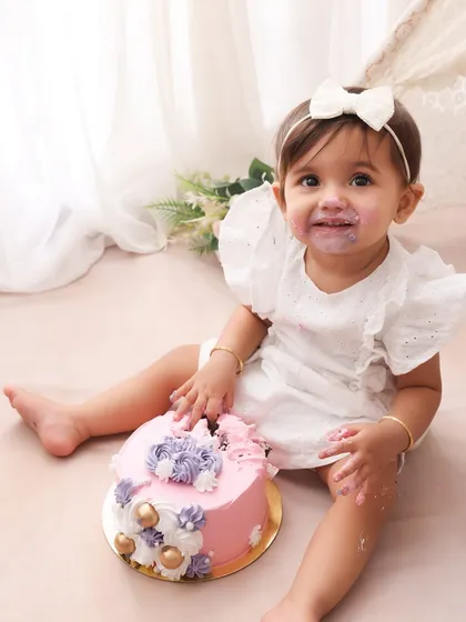 A sweet smile and a messy face. This little girl is enjoying her first birthday cake in our lovely boho-themed setup. The combination of the pink cake and her white dress is simply adorable.