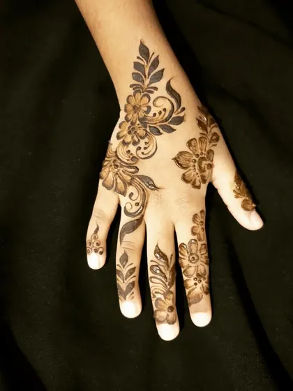 A delicate Arabic-style floral design on a child's hand.