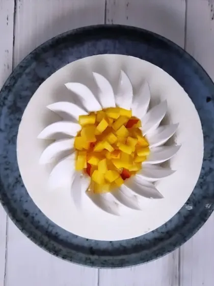 A beautifully designed mango cake with cream petals surrounding a center of diced fresh mango.
