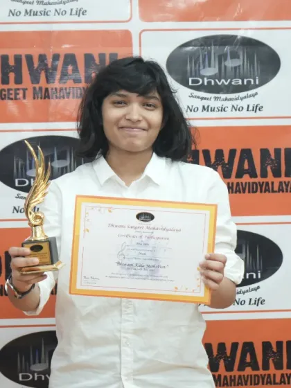 A student proudly holds her certificate and trophy for her artistic achievement.