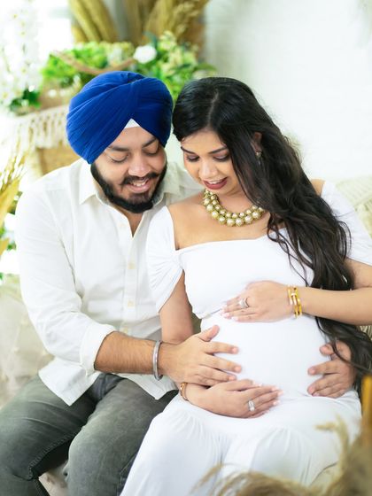 A sweet and intimate moment. This couple, dressed in white, shares a quiet moment together in our boho studio, both gently holding the baby bump.