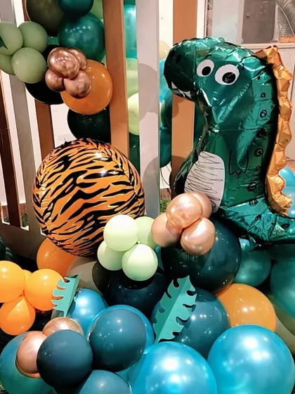 A close-up of the balloons for a dinosaur-themed party. I use themed foil balloons, like the T-Rex and a tiger-print orb, to add extra flair.