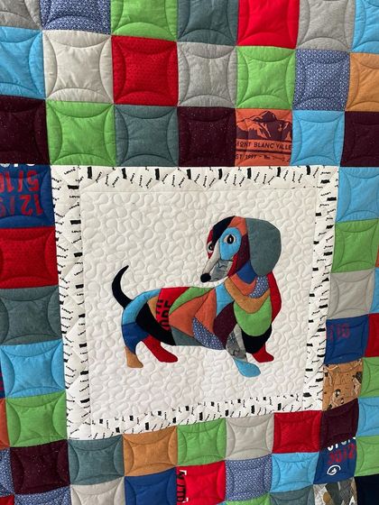 A close-up of the custom dachshund appliqué on a T-shirt memory quilt, showing the intricate stitching and fabric collage work.
