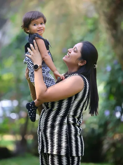 A mother lifts her daughter high in an outdoor setting. The natural light and joyful interaction make this a perfect candid shot from a family photoshoot in the park.