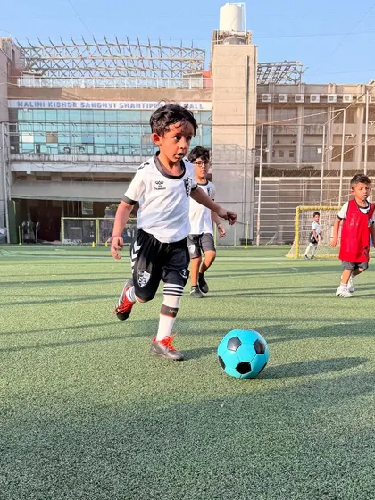 A young player runs with the ball on the open turf, building stamina and learning to control the ball while moving at speed.