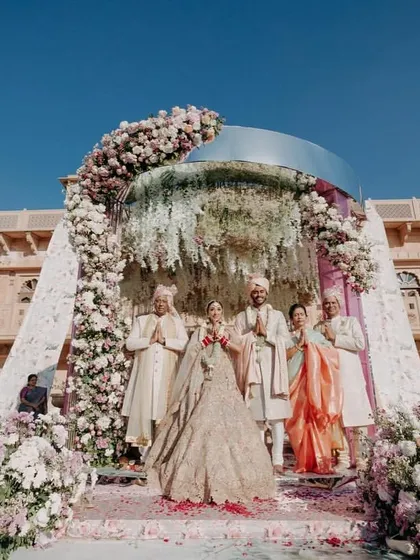 The couple and their family posing for a photograph under the magnificent floral mandap after the wedding ceremony.