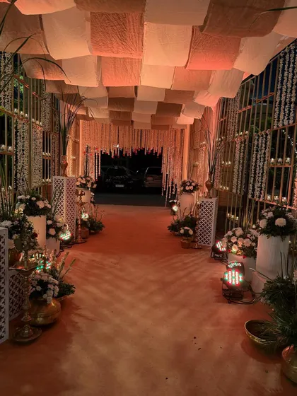 A warm and inviting entrance for an evening event, featuring a fabric-draped ceiling, candle-lit walls, and traditional floor lanterns.
