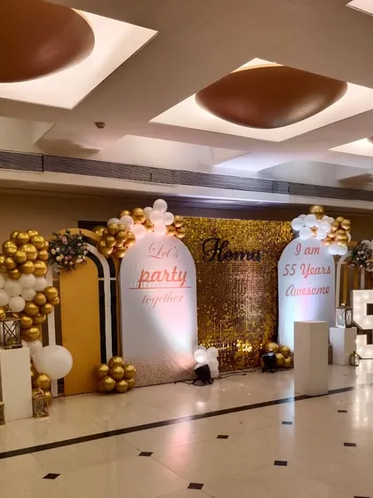 This is another angle of the 55th birthday party, showing how the balloon arches and custom backdrops create a complete and immersive environment. The combination of gold, white, and black balloons adds a touch of elegance to the event.