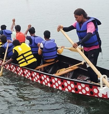 A team practices paddling in a dragon boat, a unique team-building activity offered at our Karwar camp.