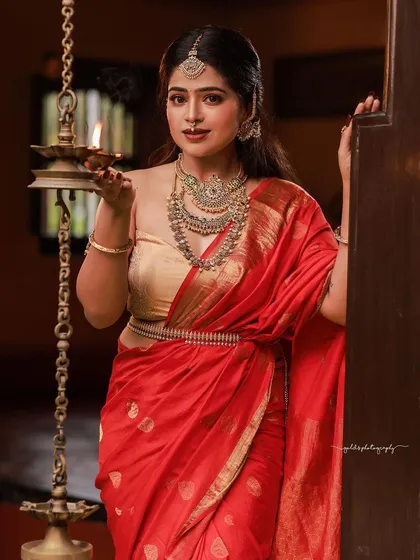 Capturing the bride in her element. Holding a traditional lamp, she is framed by the doorway of a heritage home, with the light creating a warm, inviting glow that speaks of tradition and hospitality.