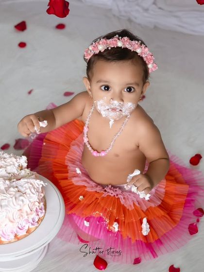 A classic cake smash with a rose theme. This little girl in a colorful tutu looks up with a face full of frosting.