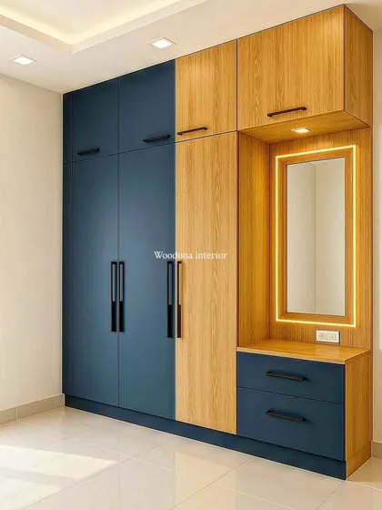 A floor-to-ceiling wardrobe doesn't have to be boring. I designed this two-tone unit in blue and wood laminate, integrating a dressing table with profile lighting. This design provides ample storage while adding a modern, stylish look to the bedroom.
