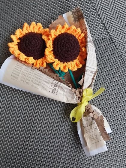 A rustic-style bouquet with two bright sunflowers, wrapped in newspaper-print paper. A charming and eco-friendly gift option.