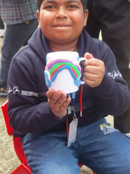 This young boy is so proud of the rainbow mug he decorated with clay at our winter carnival stall. It's a perfect example of a handmade, functional piece of art.