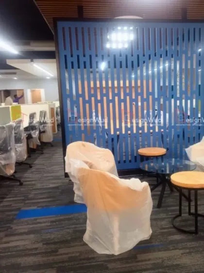 A breakout or informal meeting area situated within the main office floor. This space features a decorative blue slatted screen for partial privacy, along with comfortable seating, encouraging spontaneous collaboration among team members.