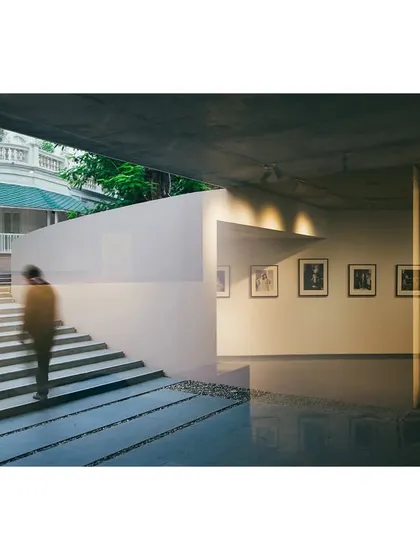 A view of the subterranean gallery at the Kasturbhai Lalbhai Museum, showing the seamless transition from the interior exhibition space to the sunken courtyard. A shallow water channel at the base of the glass reflects light into the gallery.