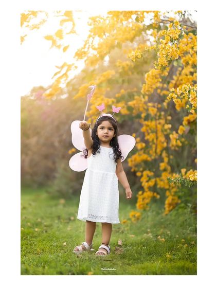 A little fairy casting a spell with her wand during a magical outdoor photoshoot.