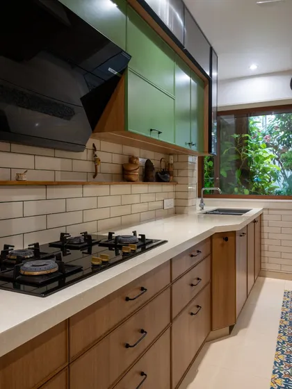This perspective emphasizes the clean lines of the countertop and the beautiful contrast between the natural wood drawers and the white subway tile backsplash. The window brings in greenery, adding a touch of life.