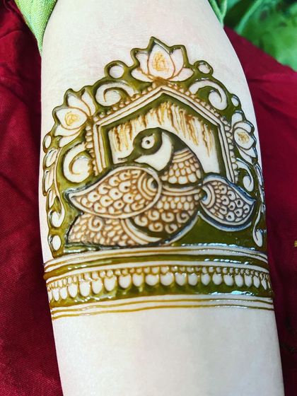 A close-up of a peacock motif framed within a jharokha, or window. The fresh green henna paste shows the detail and shading I use to bring the design to life.